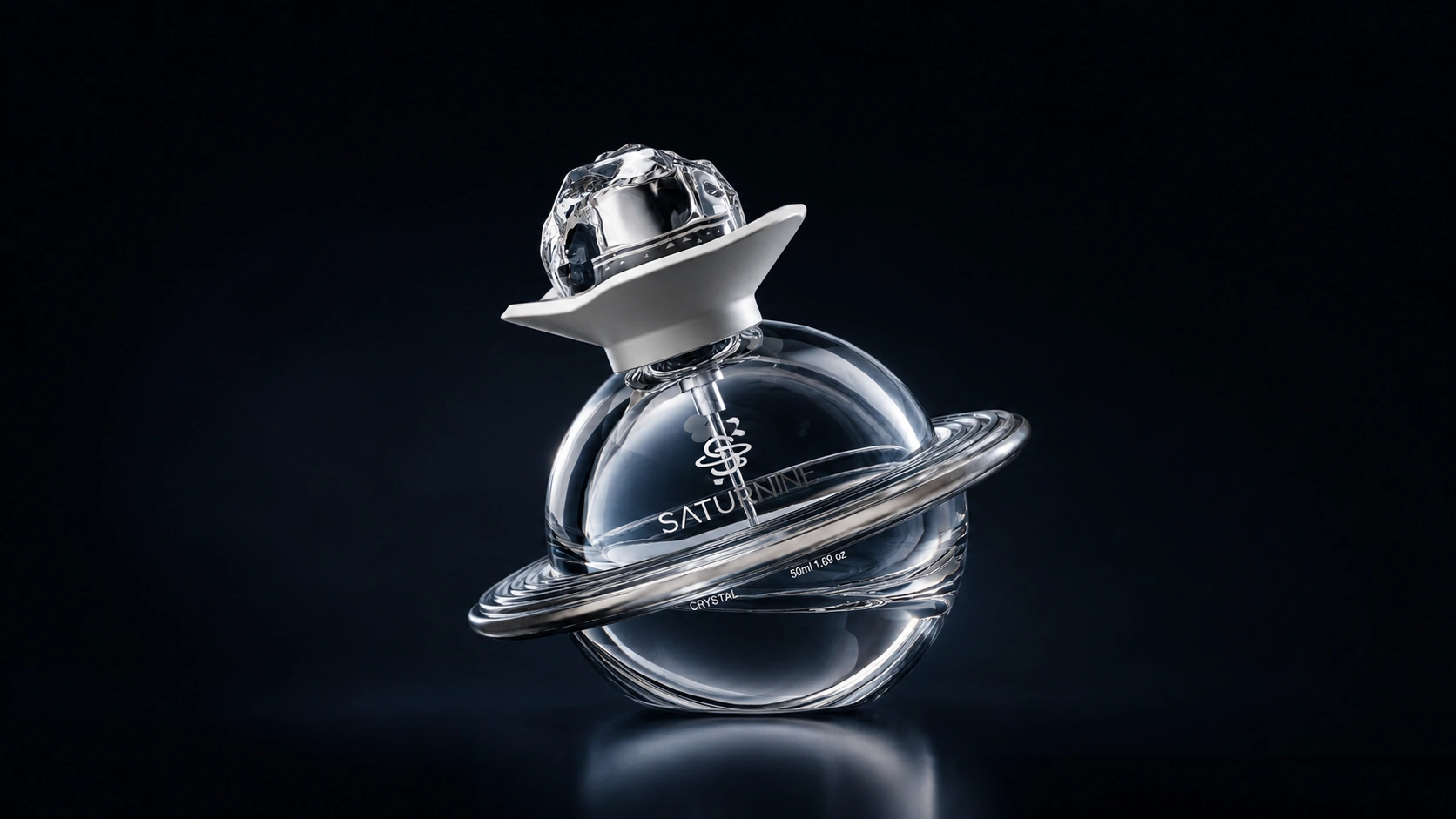 SATURNINE clear crystal bottle centered on deep navy: transparent sphere and ring, white collar and faceted cap, with a soft reflection.