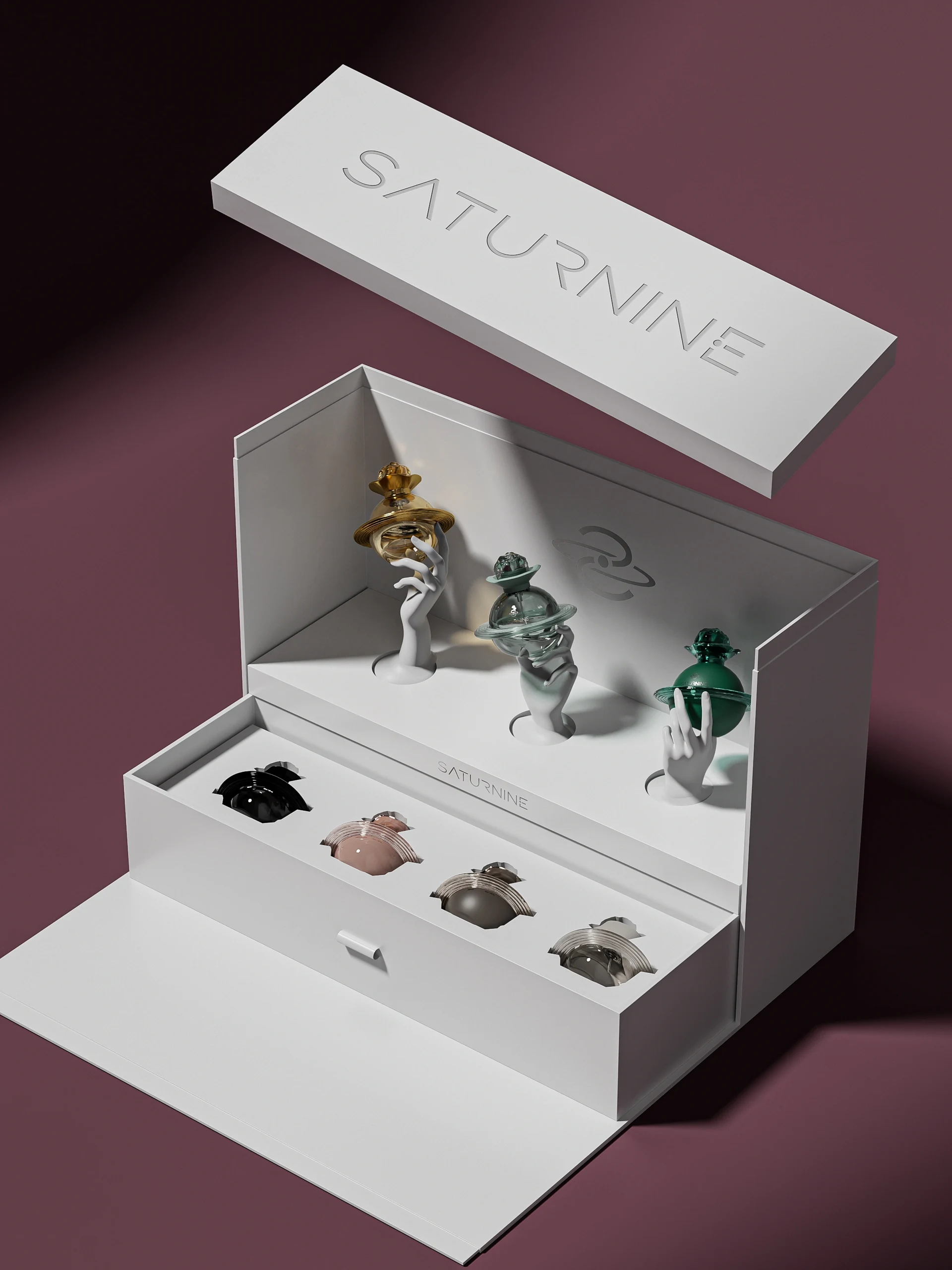 SATURNINE collector gift box: white box with lifted debossed lid, three bottles on sculpted hands above a drawer holding four more bottles.